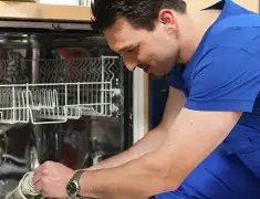 Dishwasher repair technician inspecting and servicing an open dishwasher in Long Beach, CA