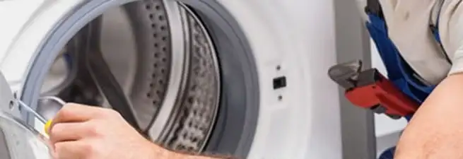 Appliance technician repairing a clothes dryer drum and internal parts in Long Beach, CA