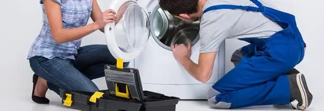 Washer repair technician inspecting a front-load washing machine with tools in Long Beach, CA