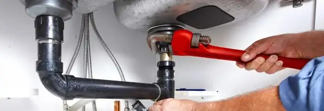 Garbage disposal repair technician tightening the sink drain and disposal connection in Long Beach, CA