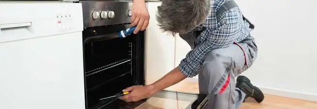 Oven repair technician inspecting and servicing an electric oven in Long Beach, CA