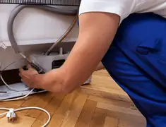 Appliance repair technician fixing refrigerator water line and connections in Long Beach, CA