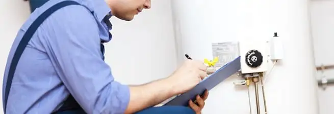 Water heater repair technician inspecting the unit and recording service notes in Long Beach, CA